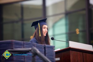 A young woman in cap and gown speaking during the 48th Commencement.