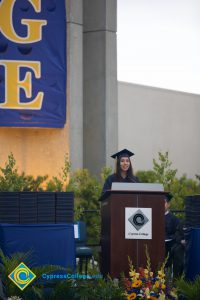 A young woman in cap and gown speaking during the 48th Commencement.