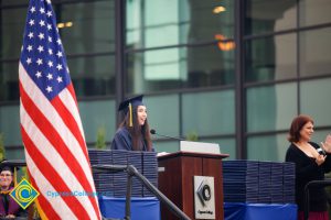 A young woman in cap and gown speaking during the 48th Commencement.