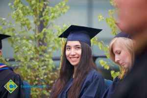 A young lady in graduation cap and gown smiling during the 48th Commencement.