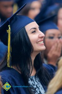 A young lady in graduation cap and gown smiling during the 48th Commencement.