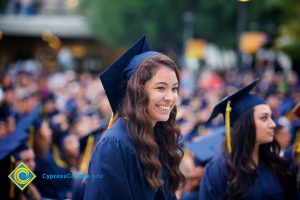 A young lady in graduation cap and gown smiling during the 48th Commencement.