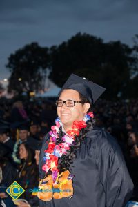 A student smiles in his cap and gown during the 48th Commencement.