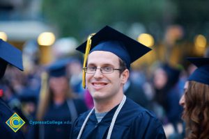 A student smiles in his cap and gown during the 48th Commencement.