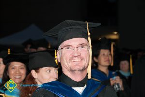 Richard Fee smiling in cap and gown during the 48th Commencement.