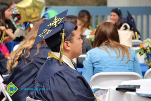 Student sitting in his cap and gown during 48th Commencement celebration.