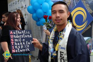 A young man in graduation gown holding his decorated cap.