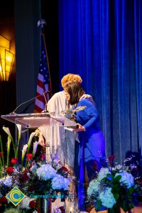 President, JoAnna Schilling hugging a woman with a blue dress.