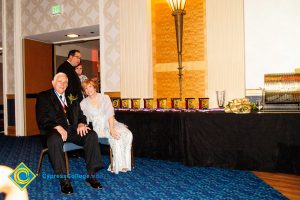 Dr. JoAnna Schilling sitting with a gentleman with a black suit and tie wearing an award around his neck.