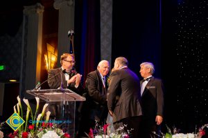 A group of men in black suits huddled on stage.