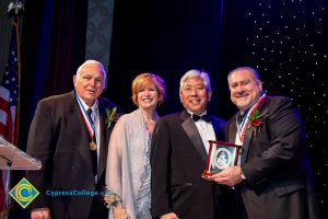 A group of men in black suits with Dr. JoAnna Schilling on stage.