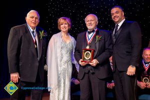 A group of men in black suits with Dr. JoAnna Schilling on stage.