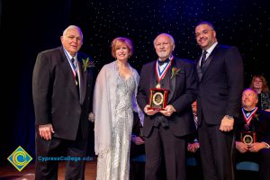 A group of men in black suits with Dr. JoAnna Schilling on stage.