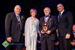 A group of men in black suits with Dr. JoAnna Schilling on stage.