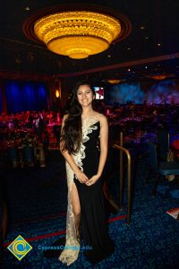 Young woman with long black hair with black dress and floral design on the front.