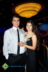 Young man in a white shirt and black tie with a young lady with black dress and white floral design.