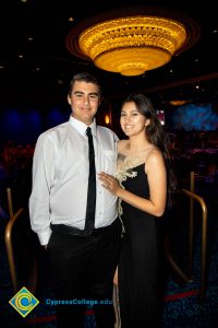 Young man in a white shirt and black tie with a young lady with black dress and white floral design.