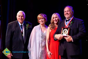 Two men in suits with awards and Dr. JoAnna Schilling and another woman in a pink dress.