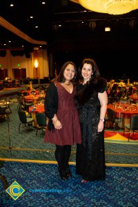 Two women with dark hair smiling.