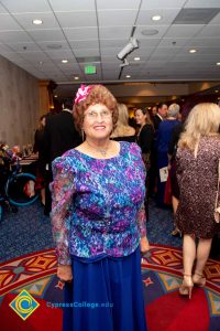 Woman in blue dress and flower in her hair smiling.