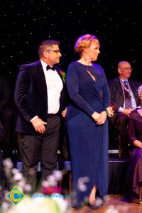 Woman in a blue dress standing with a man in a suit.