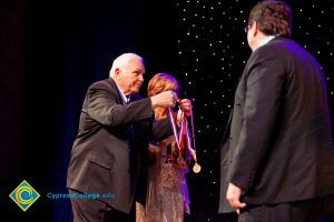 Man in a suit holing award medals.