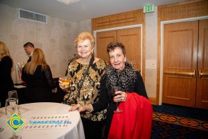 Two women smiling and holding a drink.