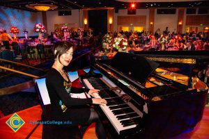 A woman dressed in black and smiling while playing the piano.