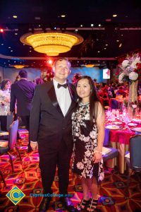 A man in a black suit and bowtie and a woman with long hair in a floral dress.