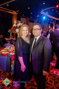 A woman in a black dress and a man with glasses, wearing a suit and tie.