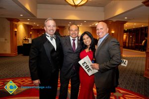 Three men in suits and a woman in a red dress.