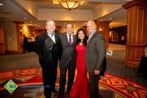 Three men in suits and a woman in a red dress.