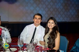 A young man in a white shirt and black tie with a young lady with long brown hair.