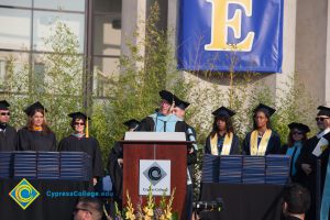 Dignitaries on stage for commencement while Preside Bob Simpson speaks to the graduates.