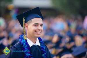 A smiling graduate wearing a blue lei.