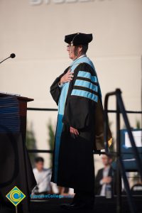 President Bob Simpson in full academic regalia with his hand over his heart.