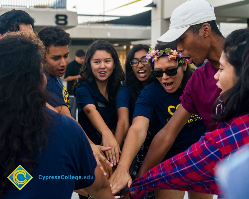 Group of students in a circle with their arms in the center