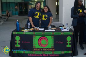 Legacy students and coordinator wearing Legacy Program t-shirts at Legacy Program table