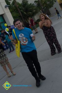 Male student wearing blue t-shirt and black pants, carrying yellow tote bag