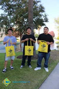Three students holding yellow Cypress College tote bags