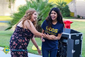 Female student wearing floral jumpsuit laughing with female student wearing navy blue Cypress College Associated Students shirt