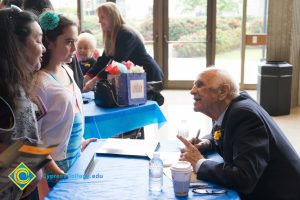 Male Holocaust survivor signing Yom HaShoah program for young girl