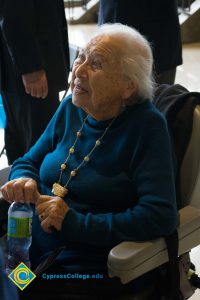 Holocaust survivor wearing blue sweater and necklace sitting in a wheelchair