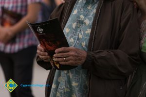 Elderly man's hands, holding Yom HaShoah program