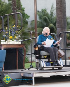 Holocaust survivor Gerda Seifer in wheelchair giving speech on stage