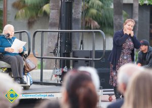 Holocaust survivor in a wheelchair giving her speech on stage while sign language interpreter translates