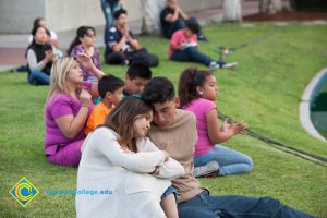 Man and woman resting their heads together while sitting on lawn