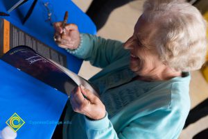 Female Holocaust survivor signing Yom HaShoah program