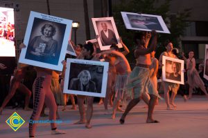 Dancers holding up photographs of Holocaust survivors