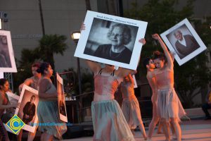 Dancers holding up photographs of Holocaust survivors